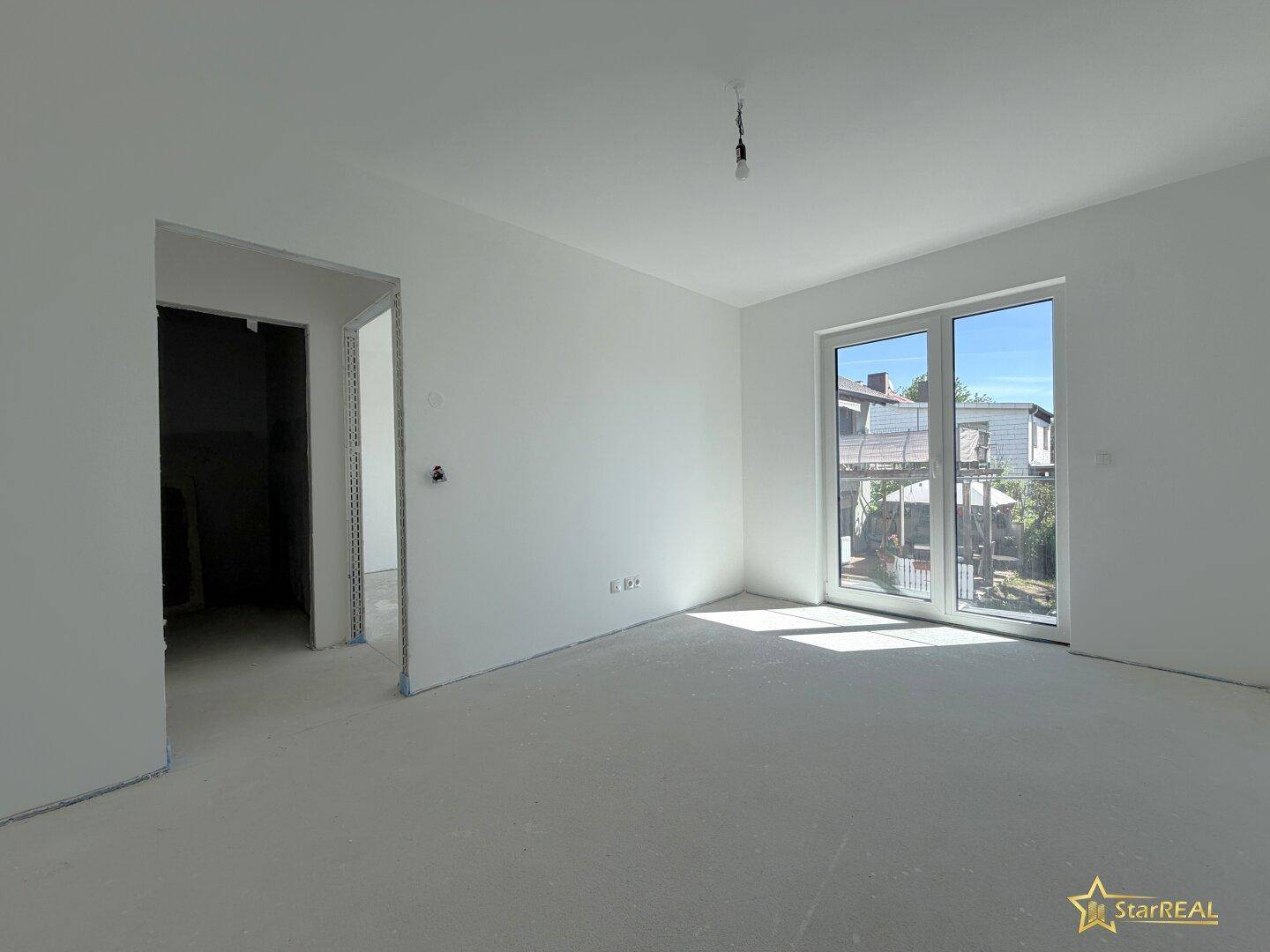 Unmöblierter Raum im Neubau mit weiß gestrichenen Wänden und großem Fenster.