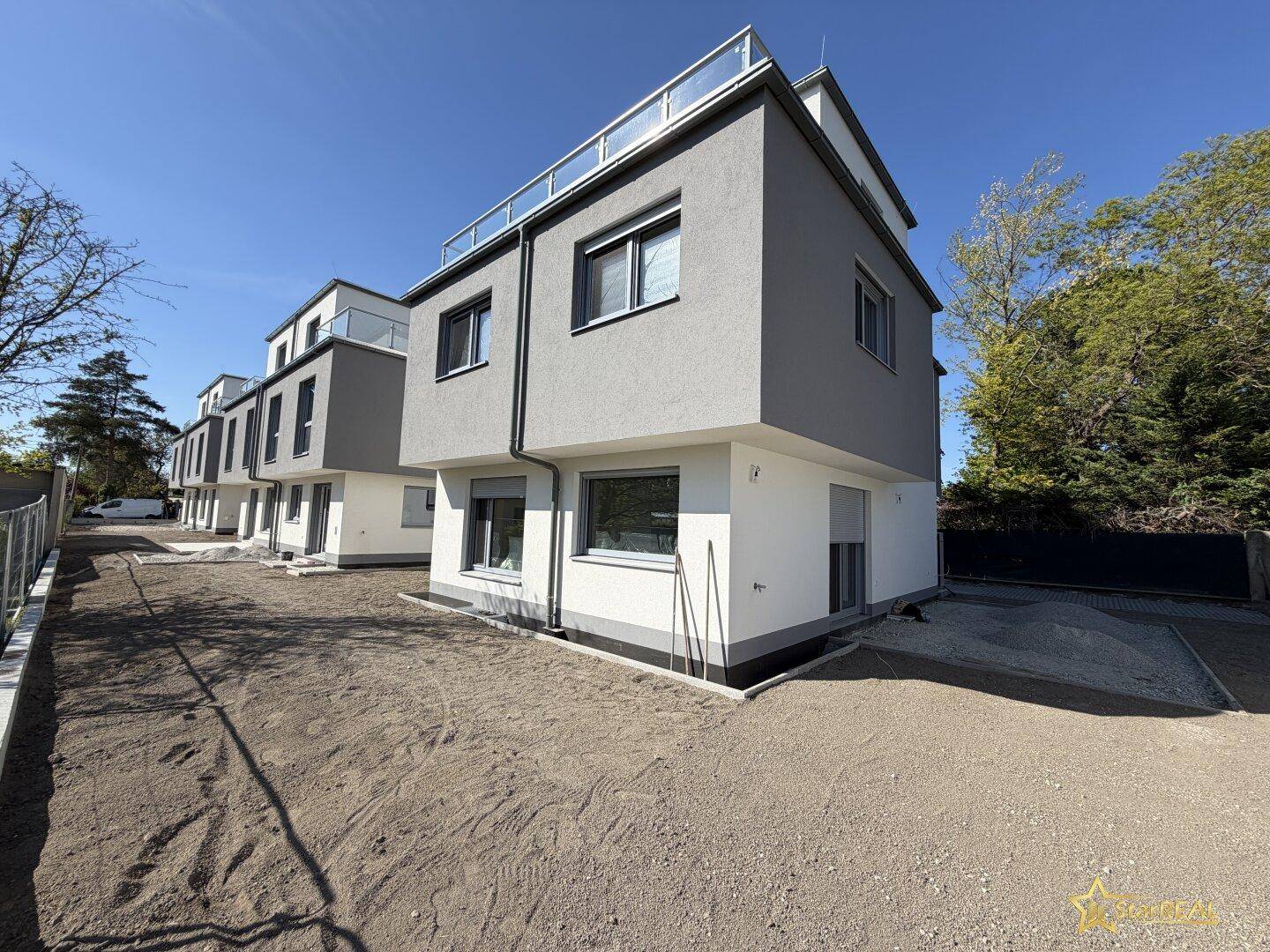 Reihenhäuser mit zeitgenössischer Architektur, großen Fenstern und vorbereitetem Außenbereich.