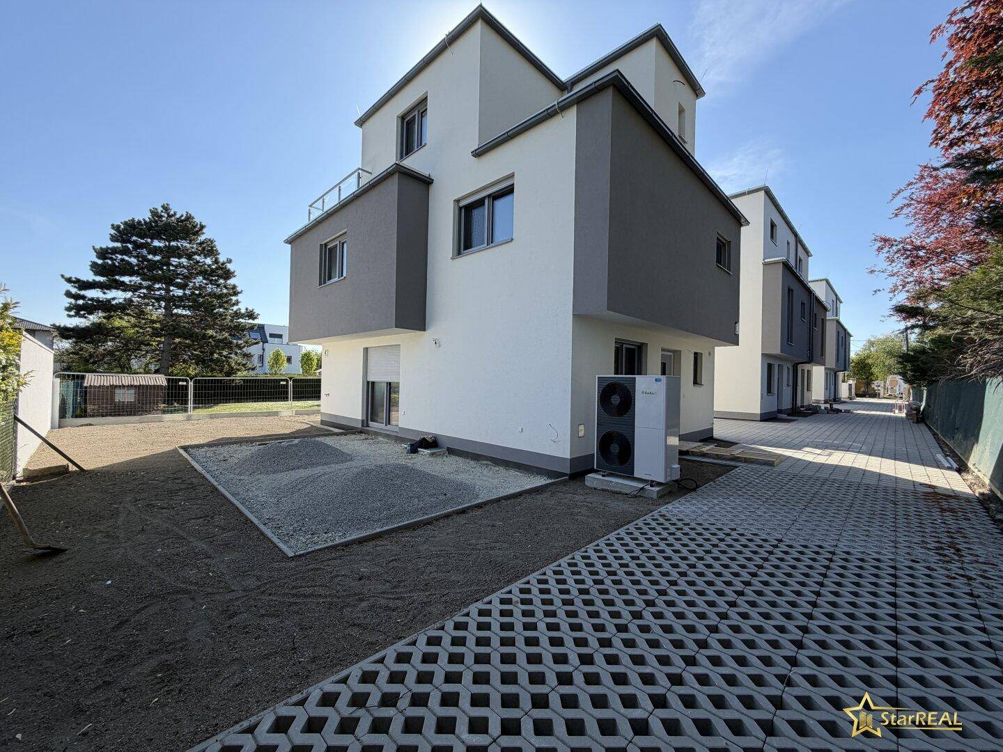 Reihenhäuser mit moderner Architektur, Wärmepumpe und vorbereitetem Außenbereich.