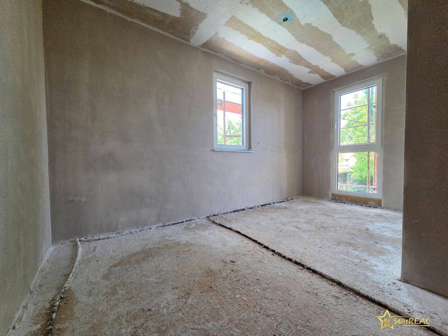 Rohbau-Zimmer mit zwei Fenstern, die den Raum hell und freundlich erscheinen lassen.