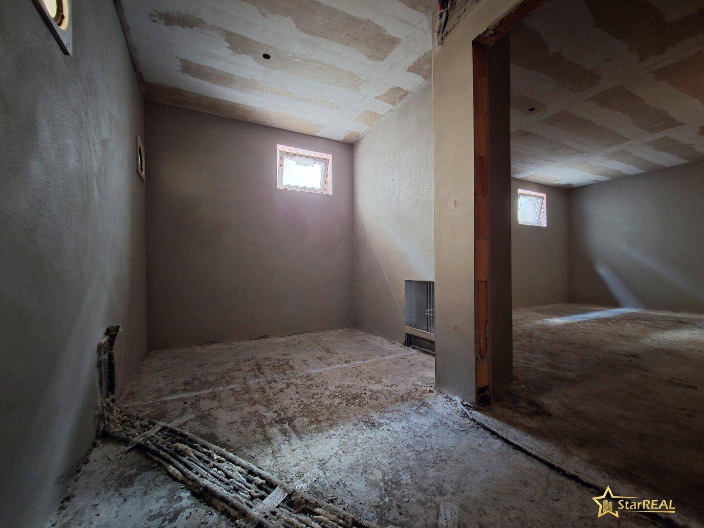 Kellerraum im Rohbau mit kleinen Fenstern und einem tragenden Pfeiler, bereit für den Ausbau.
