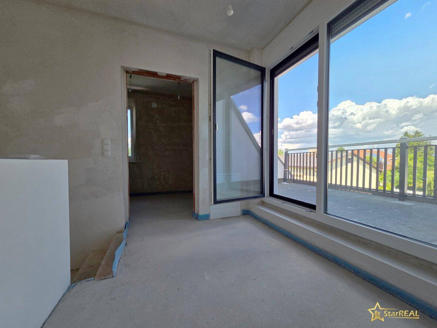 Unfertiger Raum mit Zugang zu einer Dachterrasse und viel Tageslicht.