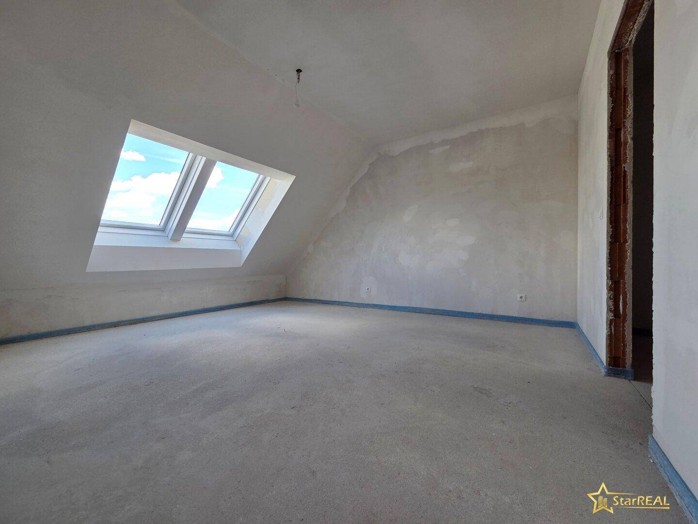Helles Dachgeschosszimmer im Rohbauzustand mit schrägen Wänden und Dachfenstern.