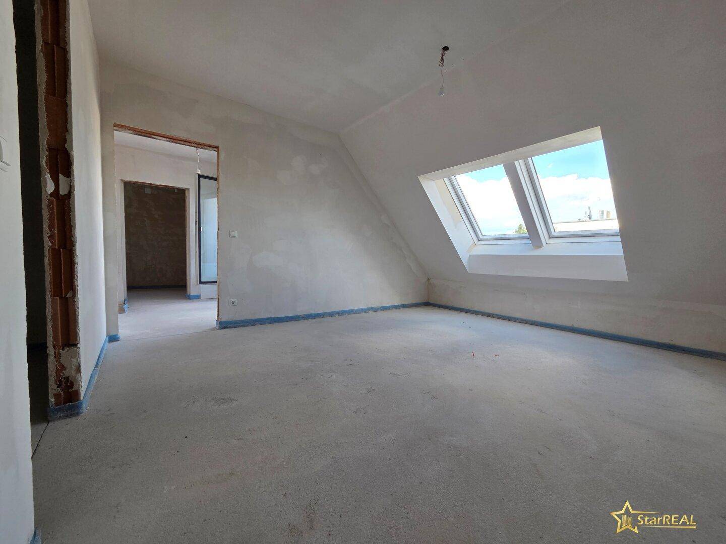 Geräumiges Dachgeschosszimmer mit Dachfenstern und Rohbauzustand.