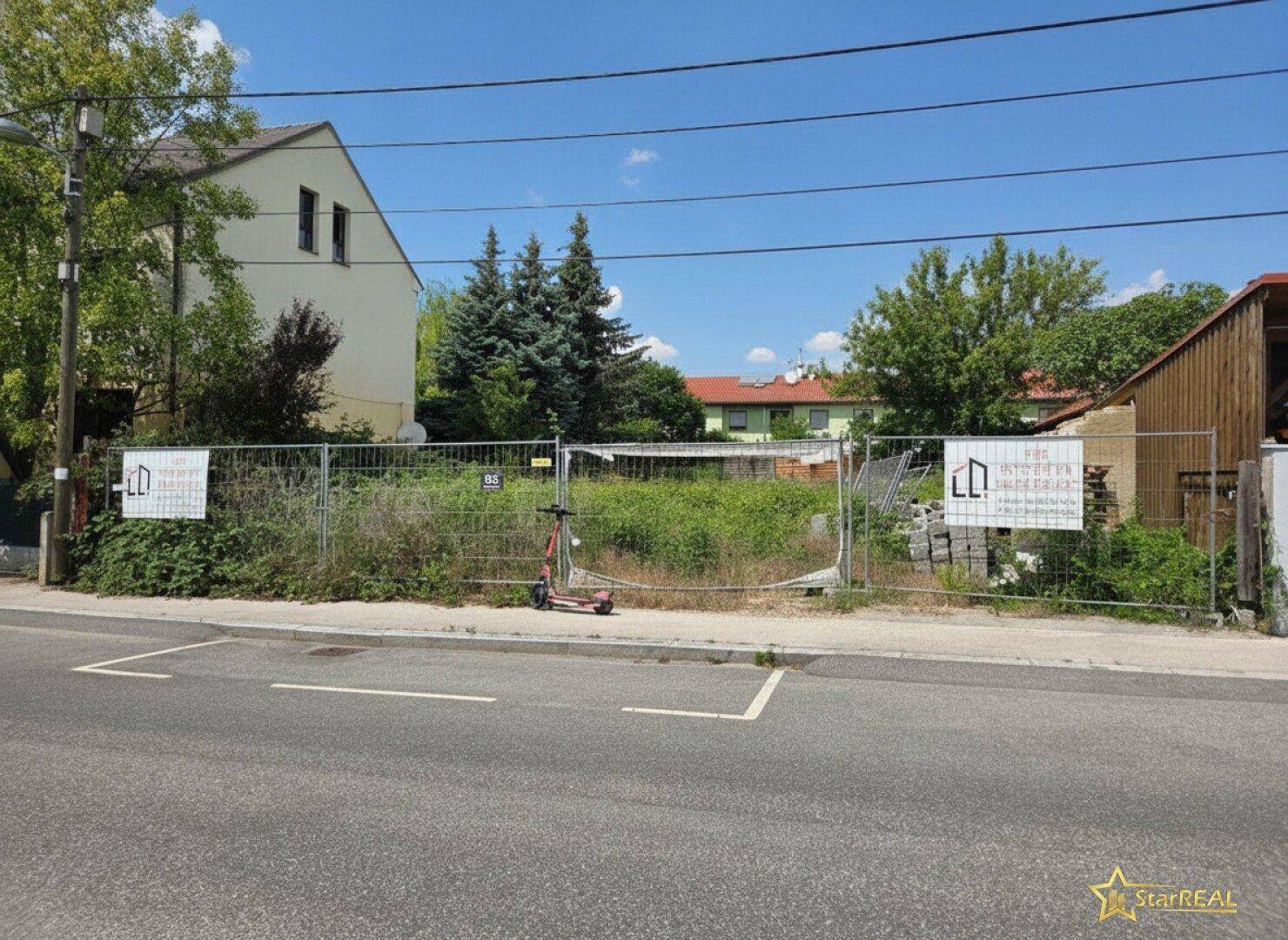 Blick auf ein eingezäuntes, unbebautes Grundstück mit Potenzial für Neubau in sonniger Lage.