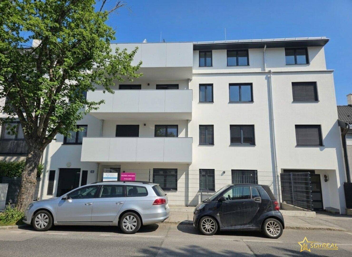 Die moderne Fassade des Gebäudes mit großen Fenstern und Balkonen, von der Straße aus gesehen.