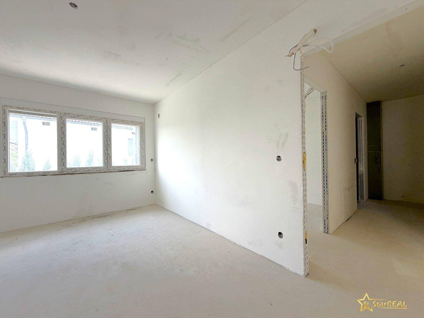 Unfertiger Raum mit drei Fenstern und weißen Wänden, bereit für den Innenausbau.