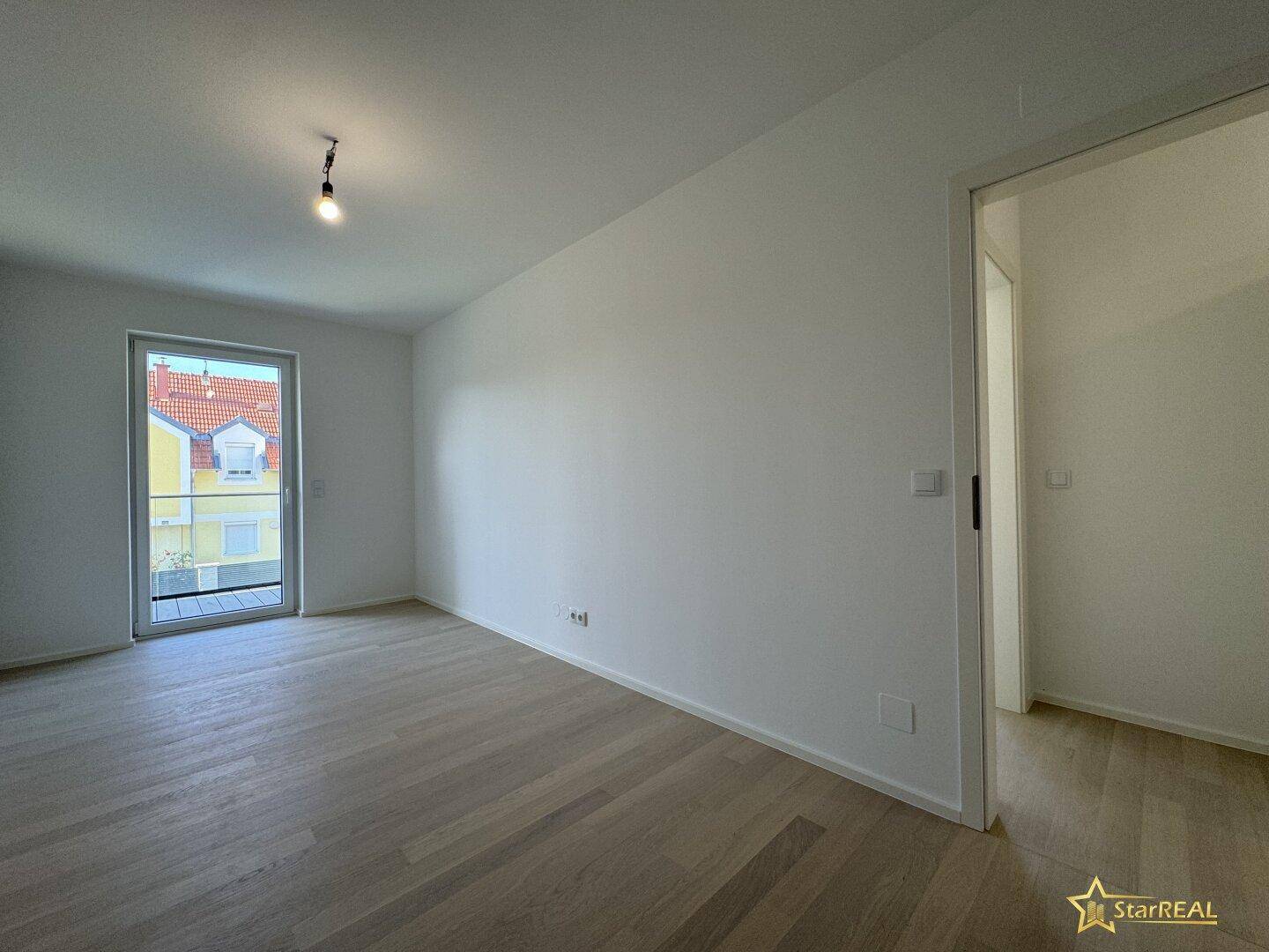 Geräumiges Schlafzimmer mit hellem Parkettboden und viel Tageslicht durch die Fenster.