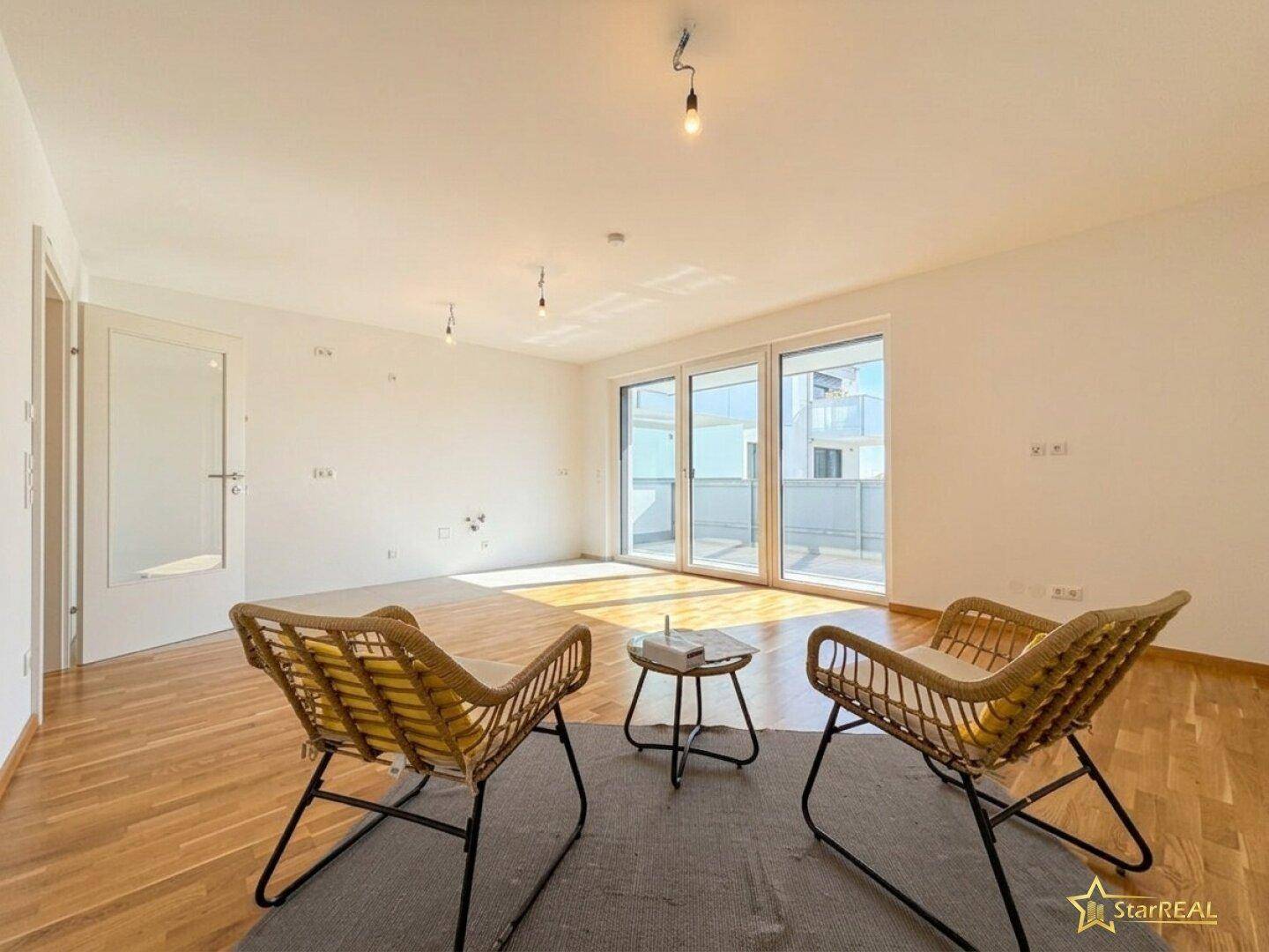 Helles Wohnzimmer mit Parkettboden, großen Fenstern und Zugang zu einem modernen Balkon.