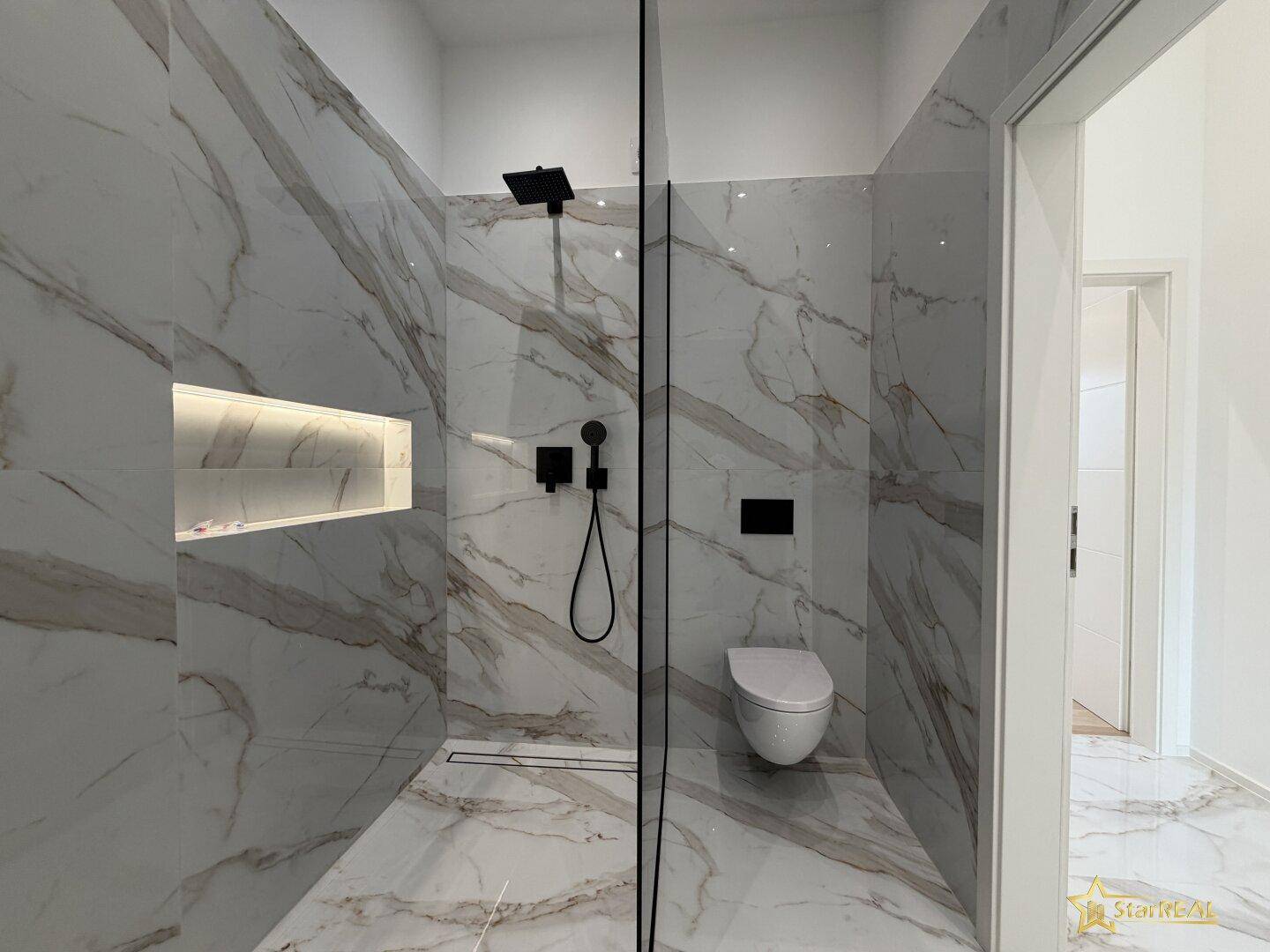 Modernes Badezimmer mit Marmoroptik-Fliesen, begehbarer Dusche und wandhängendem WC.