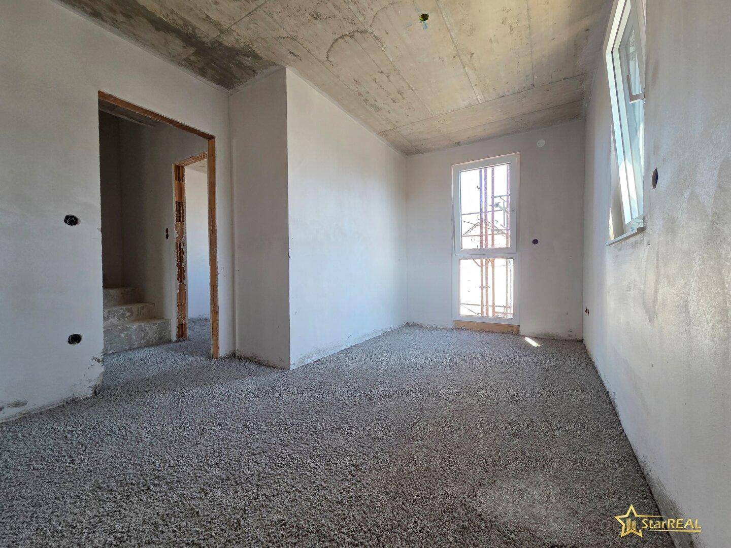 Unfertiger Raum mit Türrahmen und Fenster, bereit für den Innenausbau und Bodenbelag.