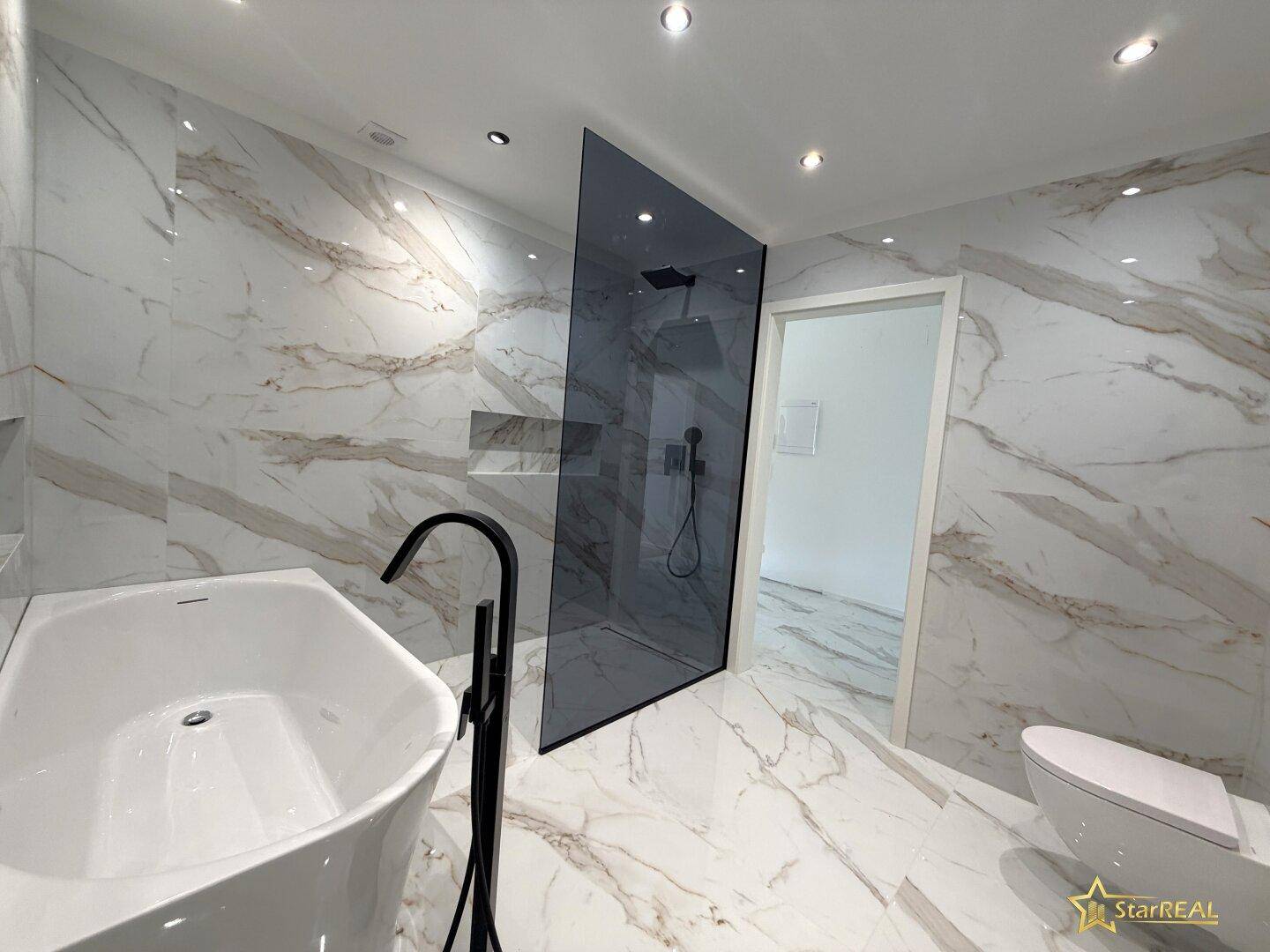 Luxuriöses Badezimmer mit freistehender Badewanne, begehbarer Dusche und hochwertigen Marmorfliesen.