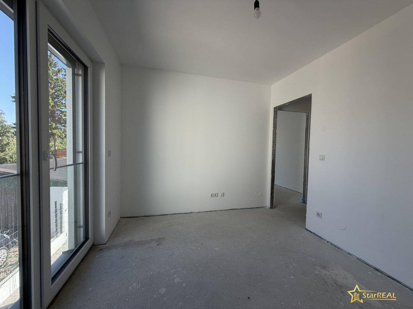 Helles, unmöbliertes Zimmer mit großem Fenster und Blick ins Grüne, bereit zum Einrichten.