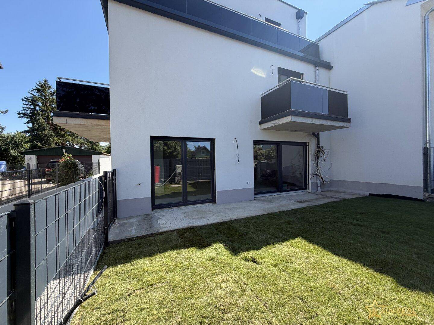 Kleiner Gartenbereich mit frischem Rasen und Zugang zum Haus durch große Terrassentüren.