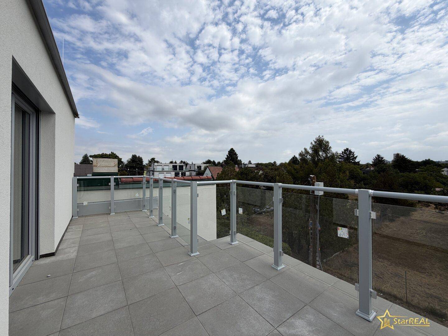 Geräumige Dachterrasse mit modernen Glasgeländern und weitem Blick über die Umgebung.