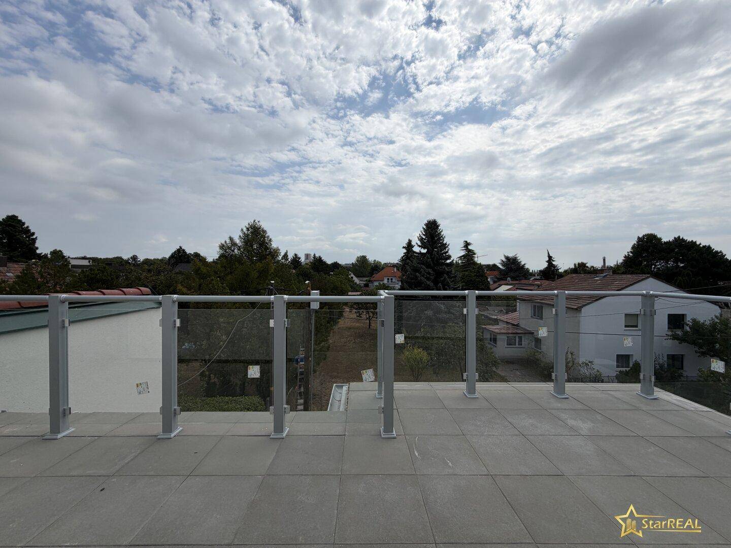 Weitläufige Terrasse mit Glasgeländer bietet einen schönen Ausblick auf die grüne Umgebung.