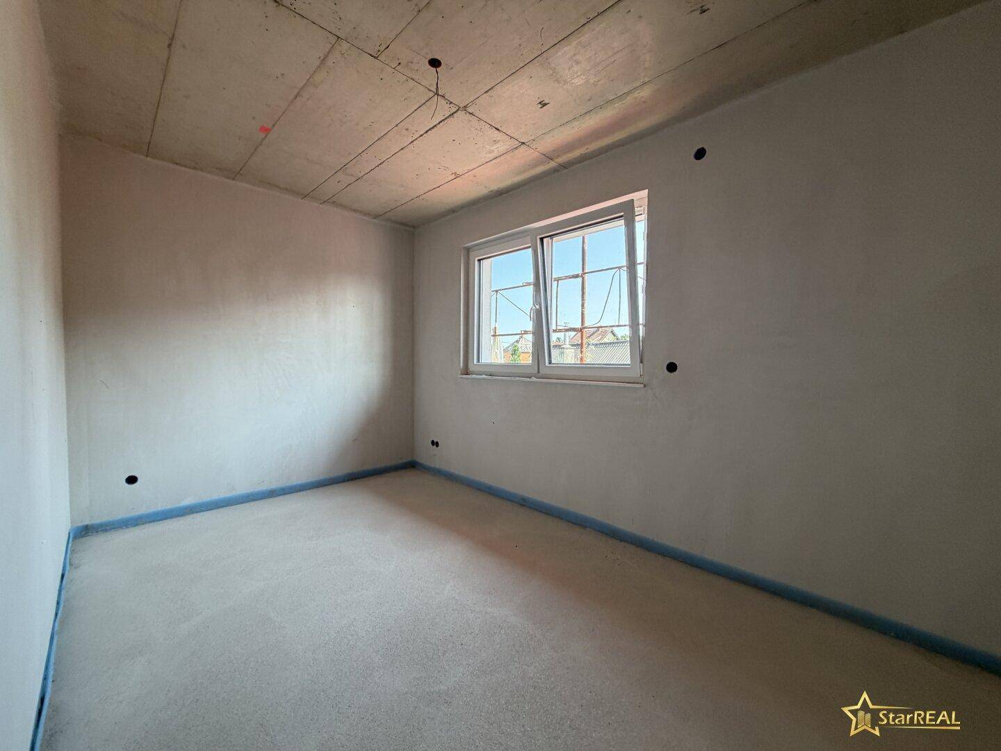 Unfertiges Schlafzimmer im Neubau mit Fenster und Betonoberflächen.