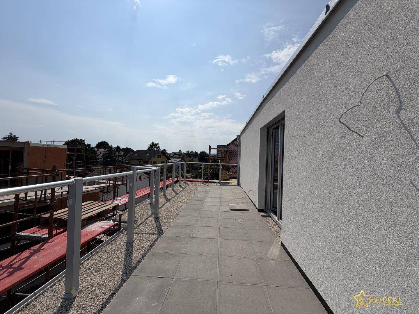 Fertiggestellte Dachterrasse mit Fliesenboden und modernem Geländer.