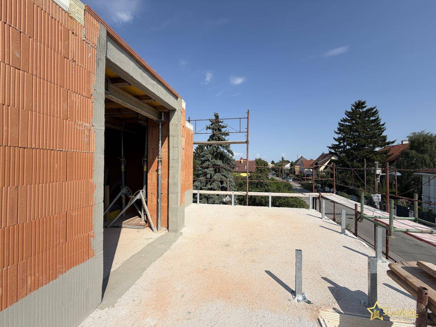 Unfertige Terrasse im Rohbau mit Blick auf die Umgebung und Gerüst.