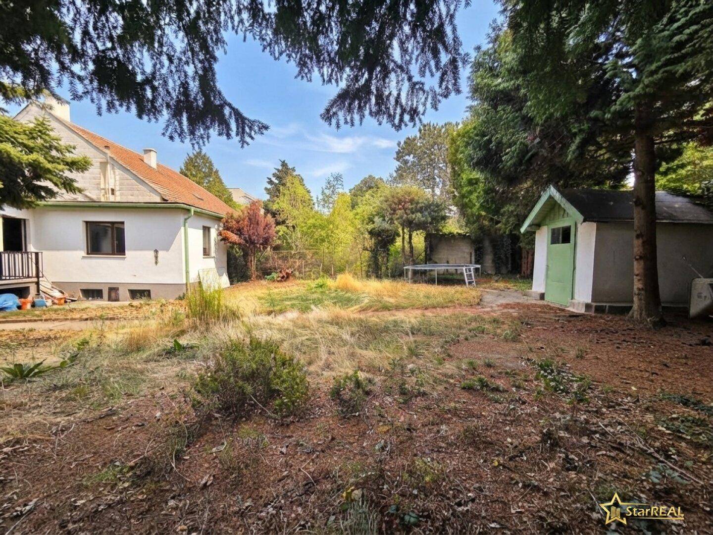 Rückansicht des Hauses mit einem weitläufigen Garten, einem Gartenhaus und einem Trampolin.