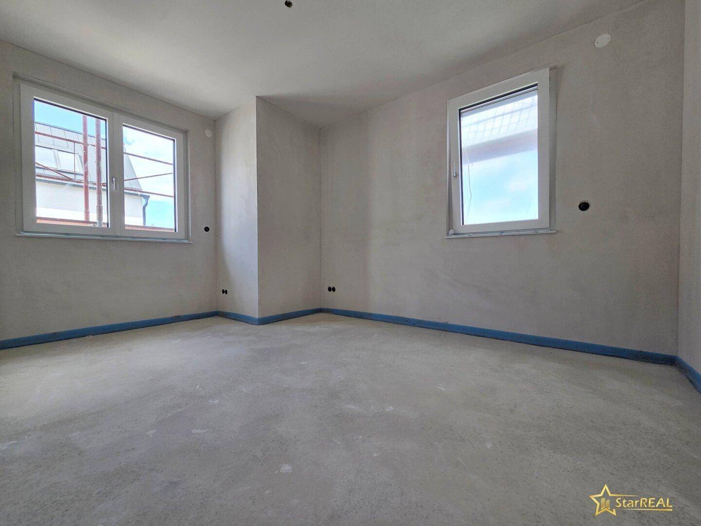 Helles Schlafzimmer im Rohbau mit zwei Fenstern und viel Potenzial für die Gestaltung.