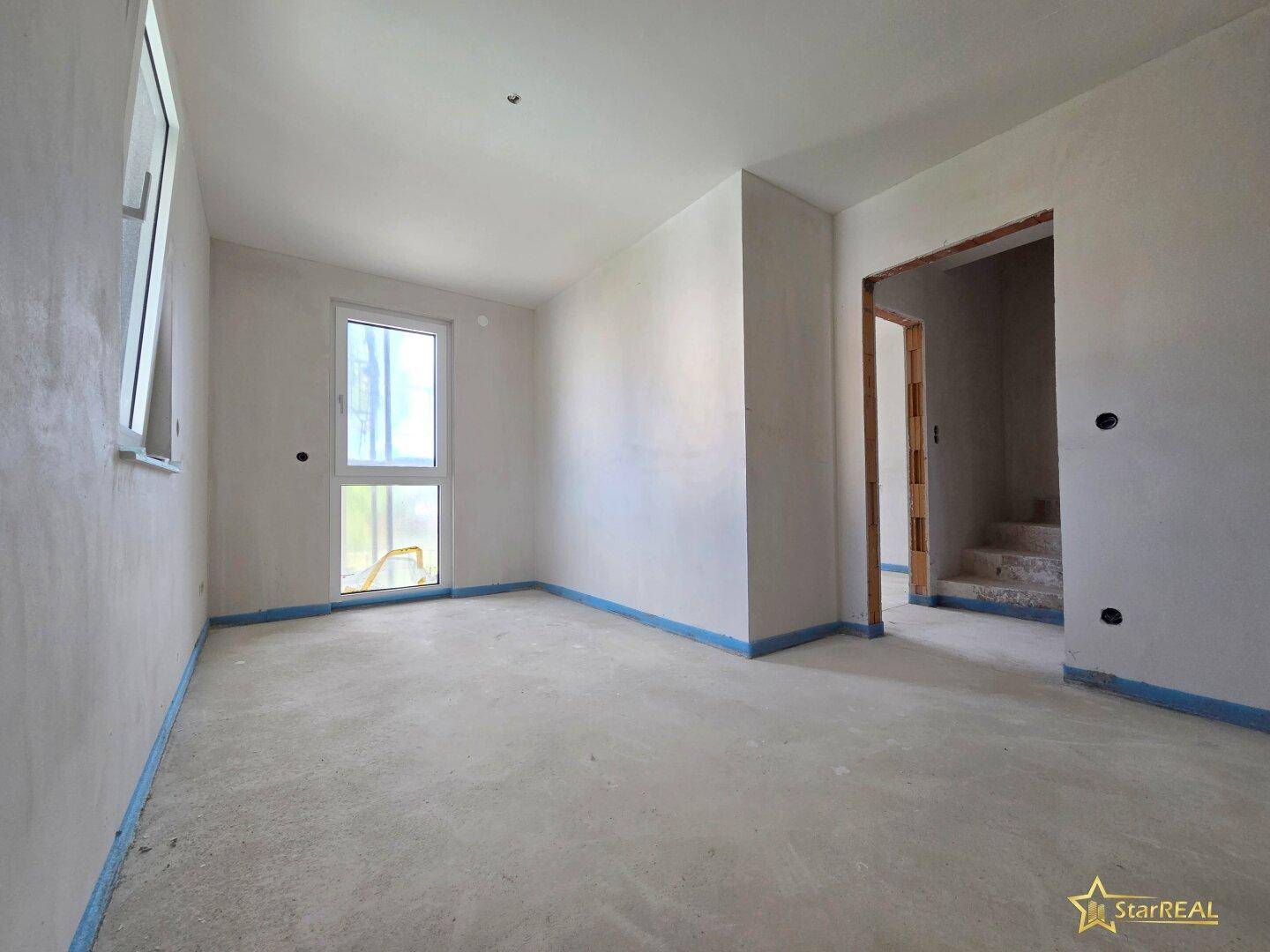 Rohbauzimmer mit Fenster und Türöffnung, bereit für die weitere Innenausstattung.