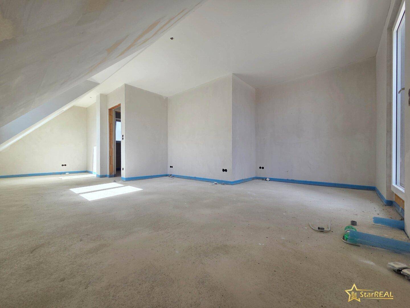 Geräumiges Dachgeschoss im Rohbau mit schrägen Wänden, bereit für den Innenausbau.