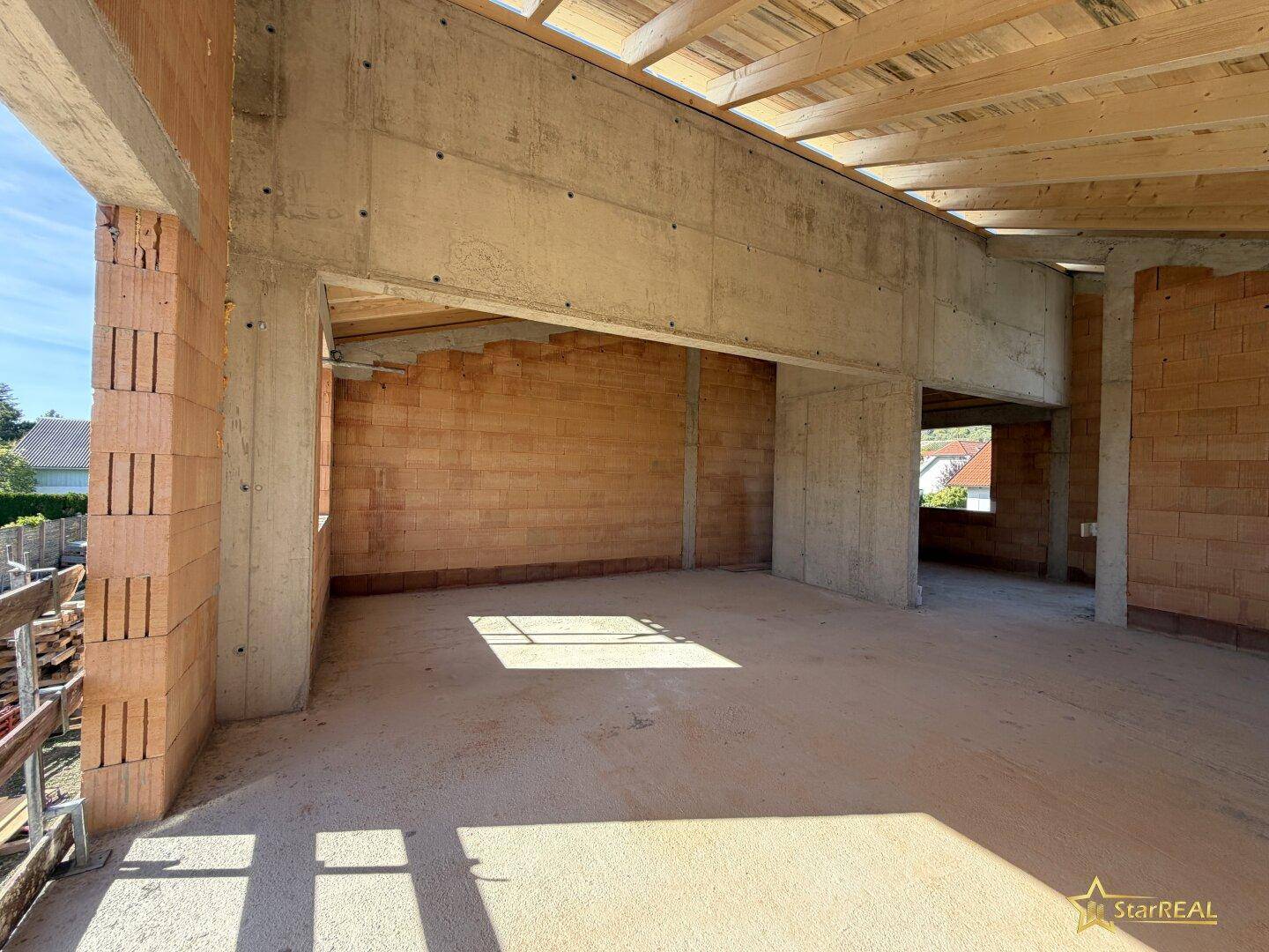 Offener Raum im Obergeschoss mit Betonbalken und Holzdach, bietet viel Gestaltungspotenzial.