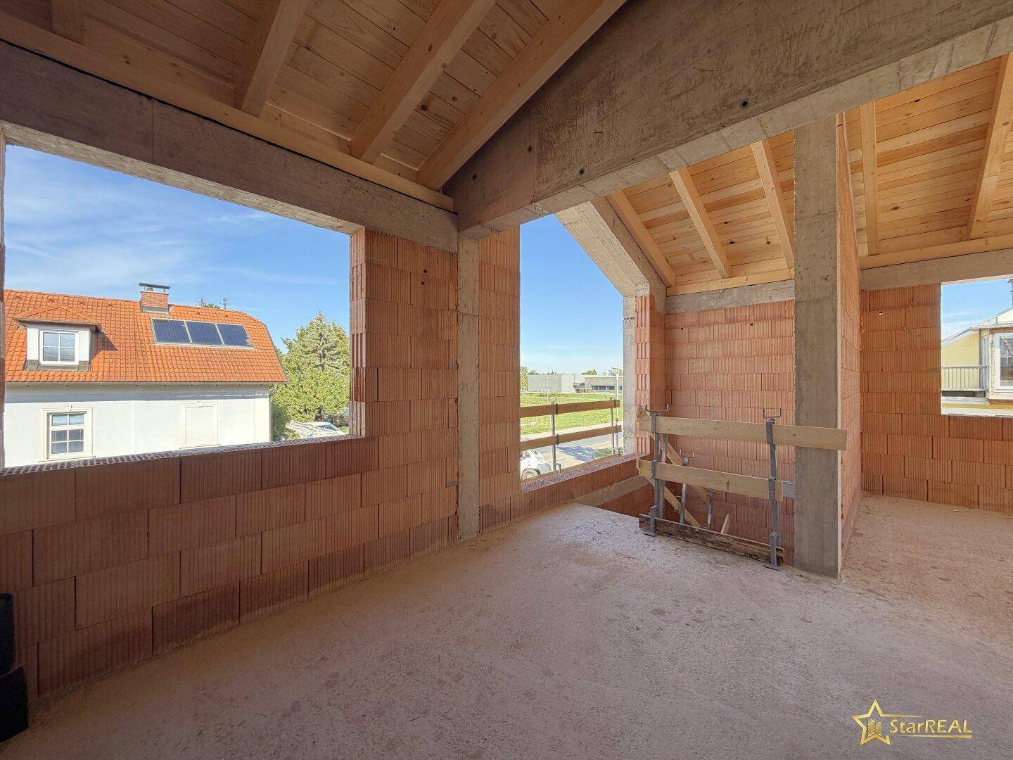 Heller Raum im Obergeschoss mit Holzdach und Ziegelwänden, bietet einen weiten Blick ins Grüne.