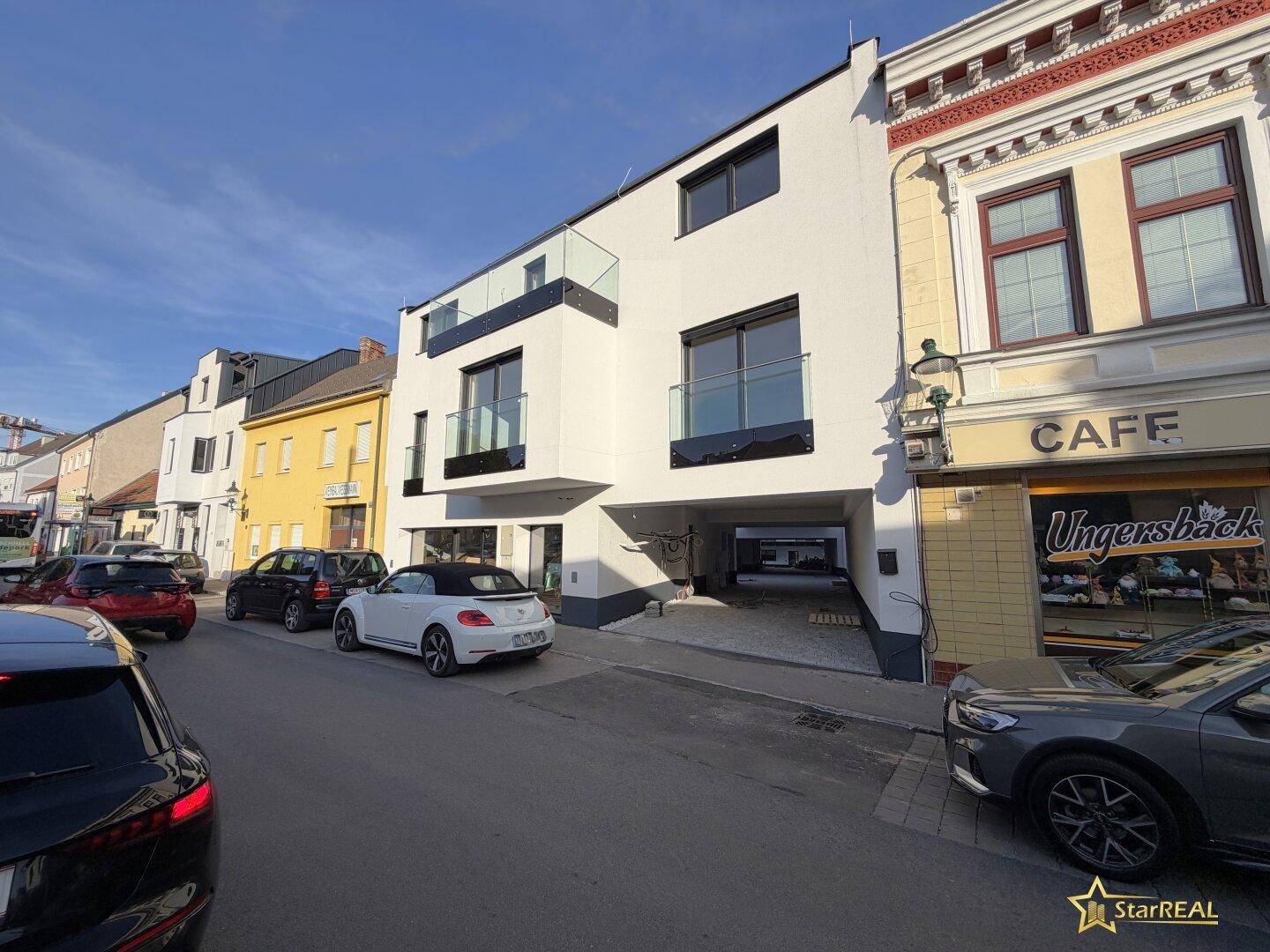 Straßenansicht des modernen Gebäudes mit Balkonen und umliegenden Häusern.