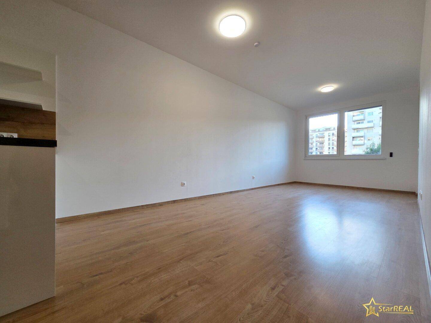 Geräumiges, helles Wohnzimmer mit Laminatboden und großen Fenstern, bereit zur individuellen Gestaltung.
