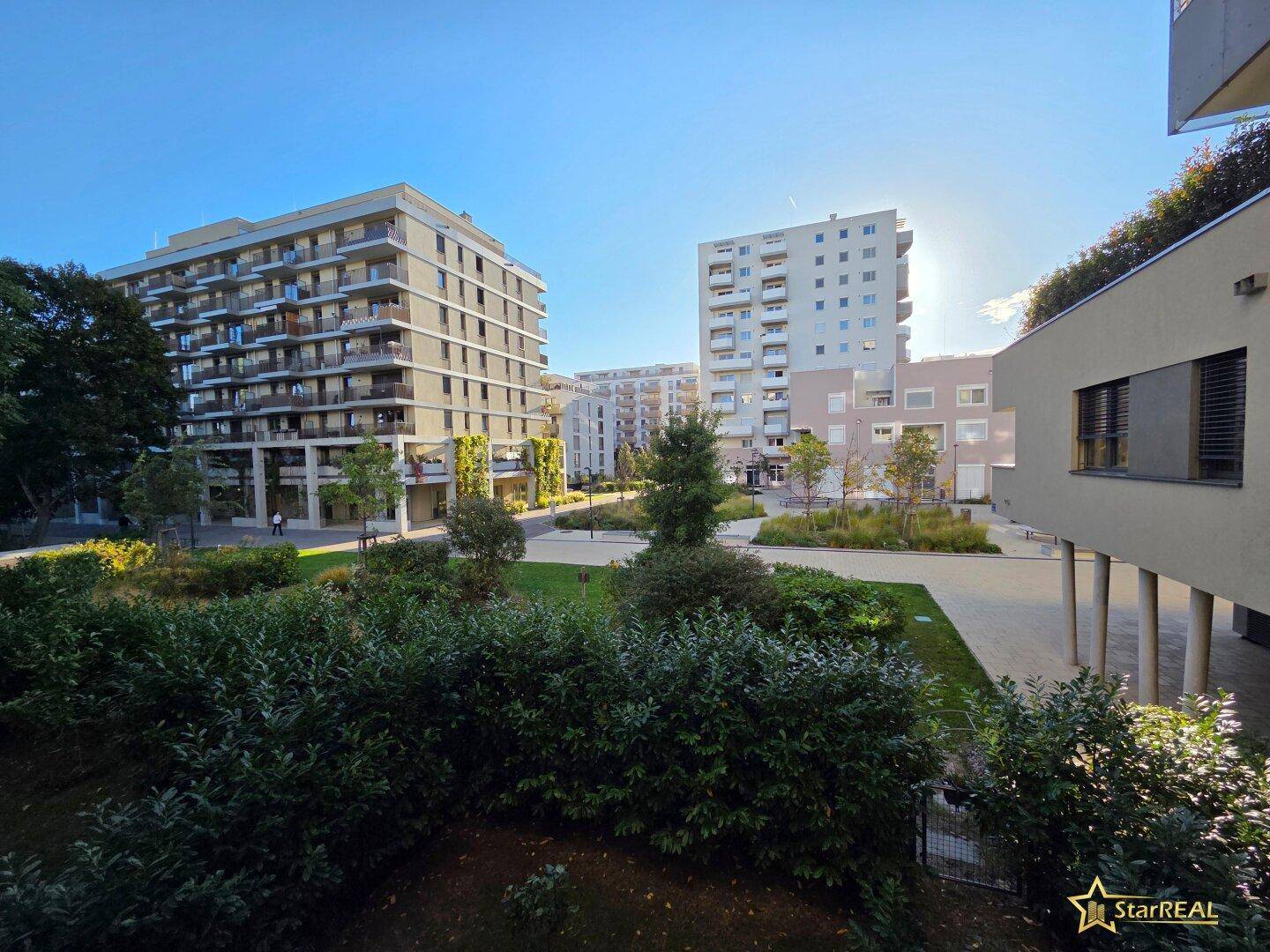Weitläufige Außenanlage des Wohnkomplexes mit gepflegten Grünflächen und modernen Gebäuden.