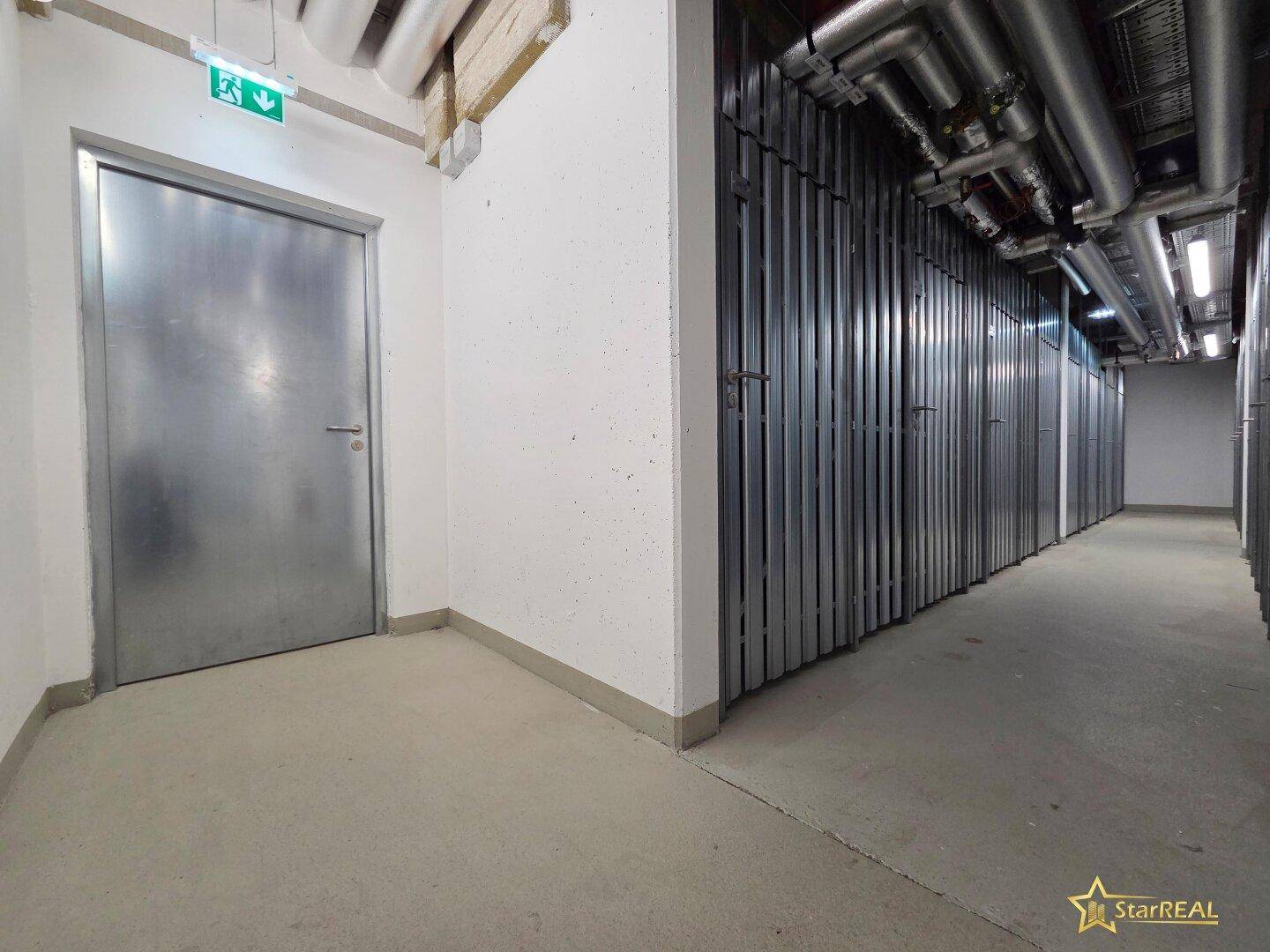 Kellerabteil mit Metallwänden und sichtbaren Rohren in einem Mehrfamilienhaus.