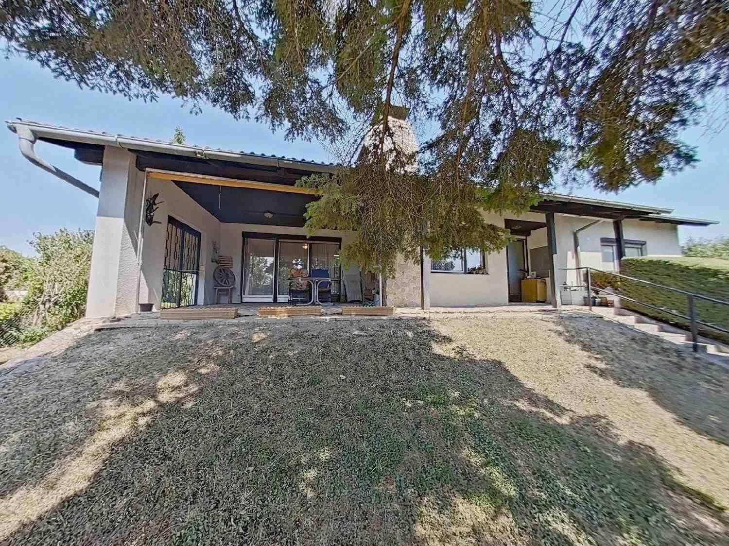 Rückansicht des Hauses mit großer Terrasse und Gartenbereich auf einem Hanggrundstück.
