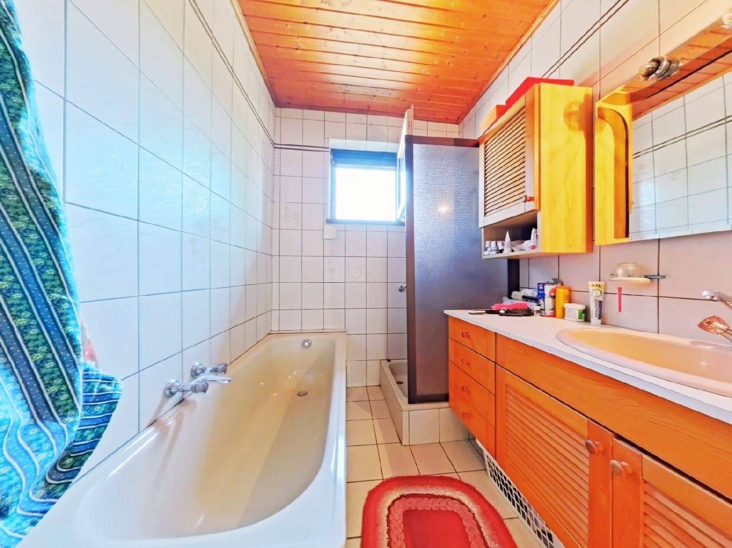 Badezimmer mit Badewanne, Holzwaschtisch und Fliesen an Wänden und Boden.