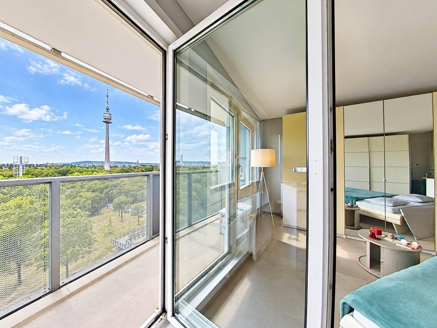 Blick vom Schlafzimmer auf den Balkon mit Glasfront und weitem Ausblick über die Umgebung.