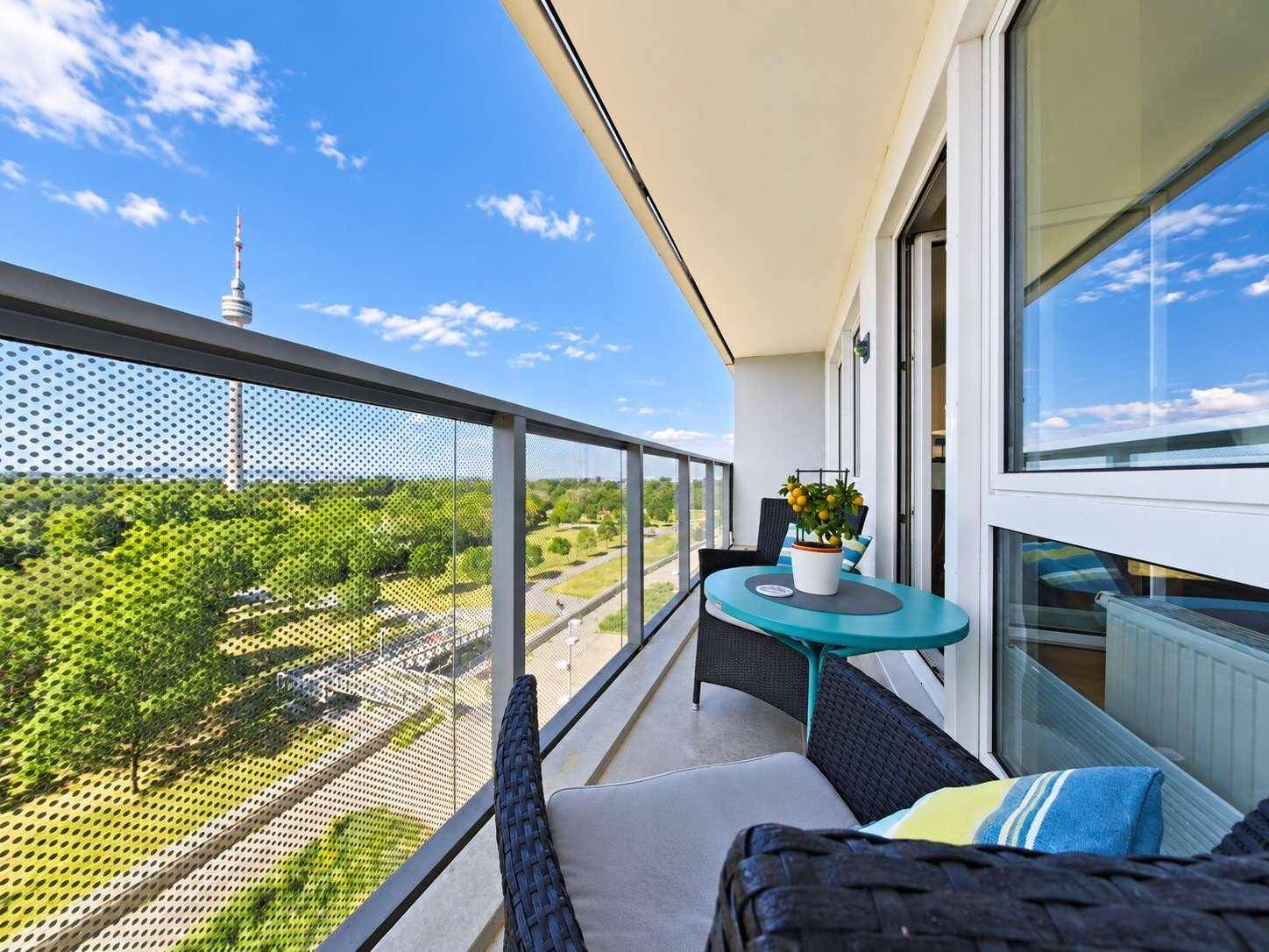 Langer Balkon mit Sitzgelegenheiten und Panoramablick über grüne Flächen und die Stadt.