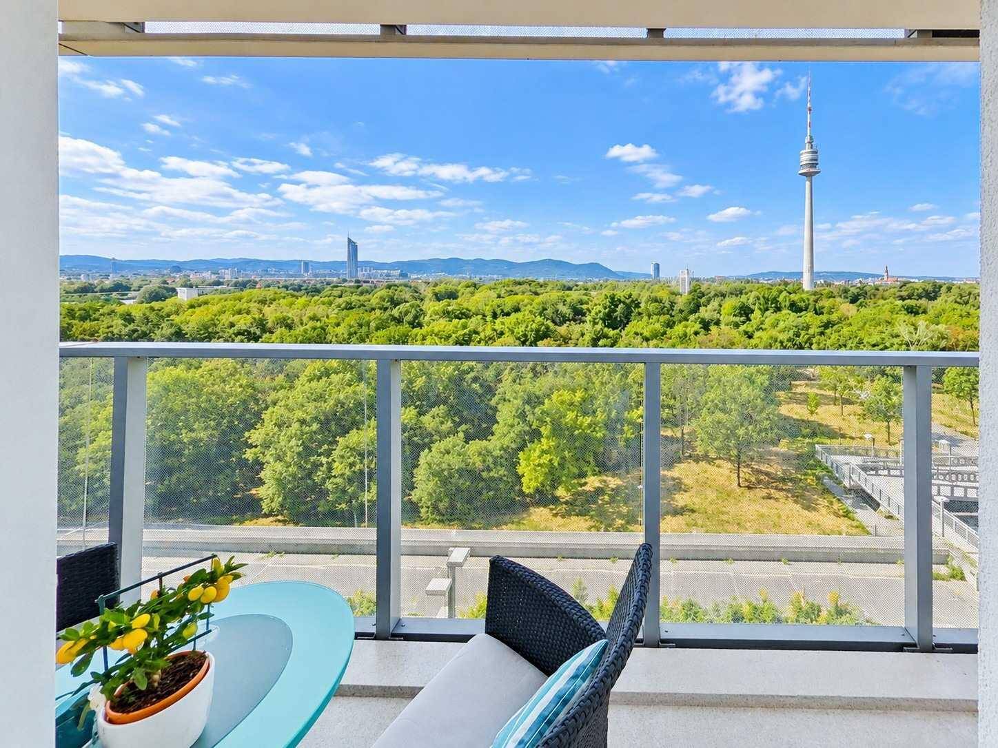 Weitläufiger Balkon mit Glasbrüstung und beeindruckendem Blick auf die Stadt und Natur.