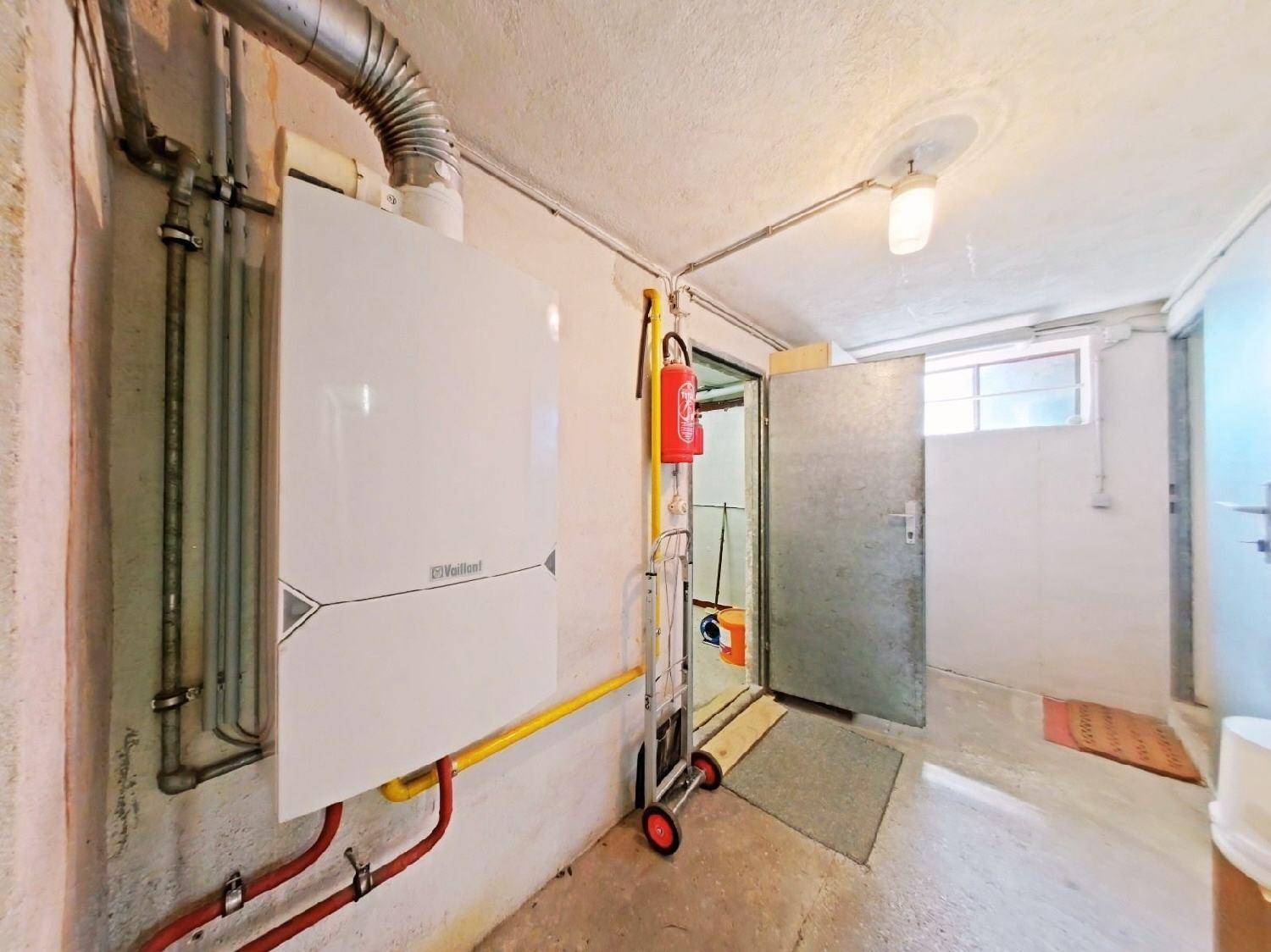 Heizungsraum im Keller mit moderner Heizungsanlage und Zugang nach draußen.