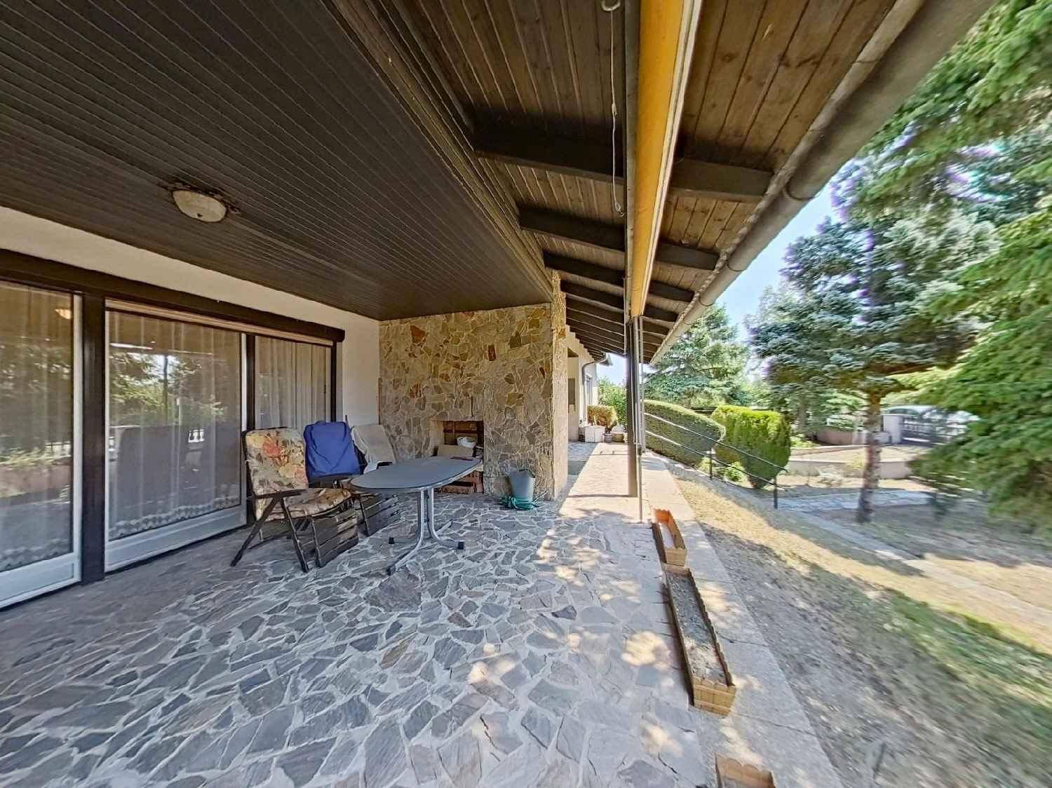 Überdachte Terrasse mit Steinboden und Gartenmöbeln, ideal für entspannte Stunden.