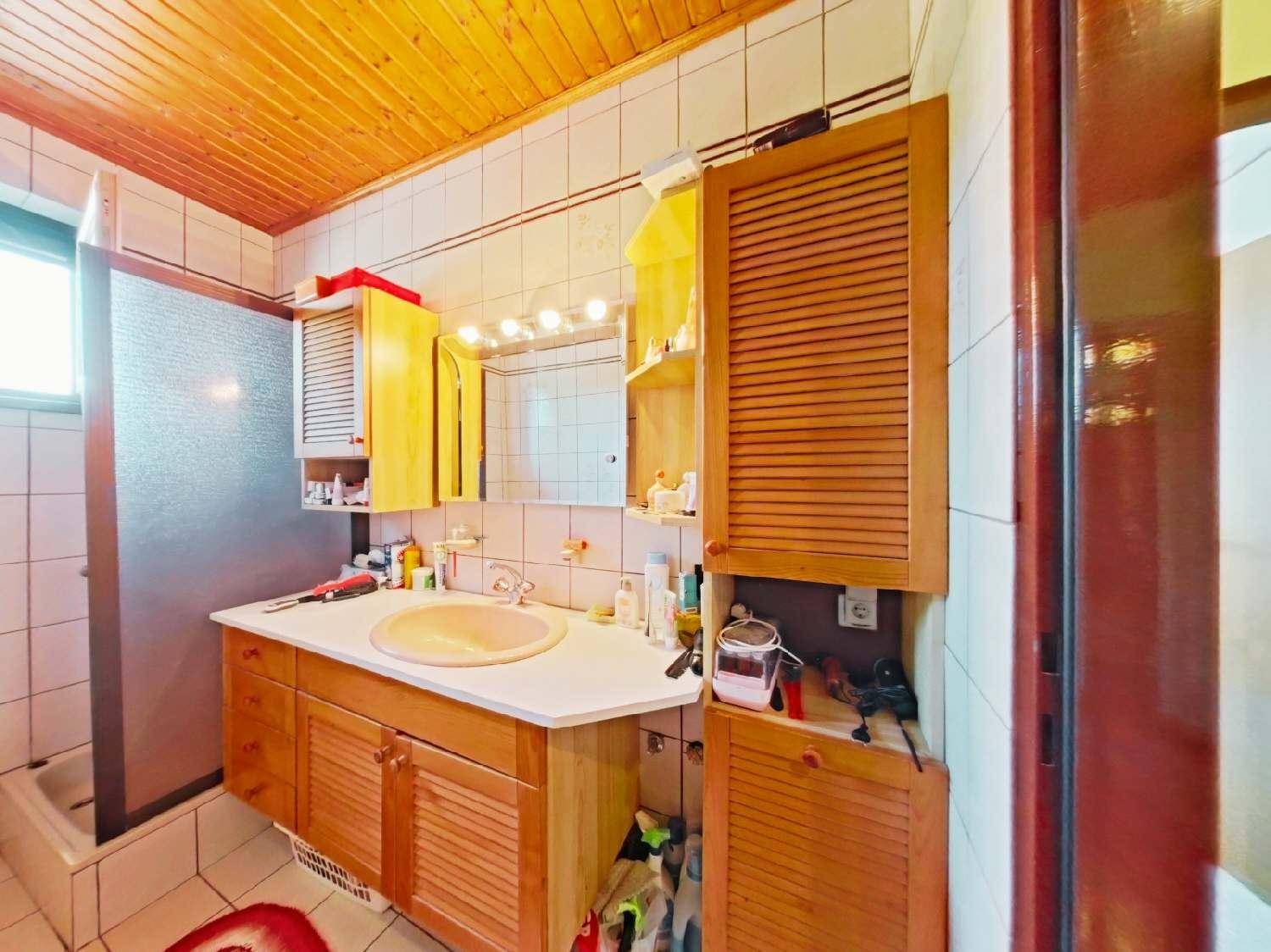 Badezimmer mit Holzwaschtisch, Spiegelschrank und Duschbereich, ausgestattet mit Holzdecke.