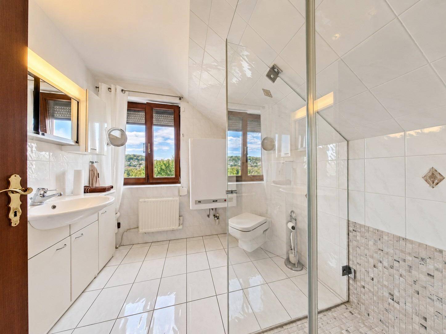 Helles Badezimmer im Dachgeschoss mit Dusche, WC und Fenster mit Weitblick.