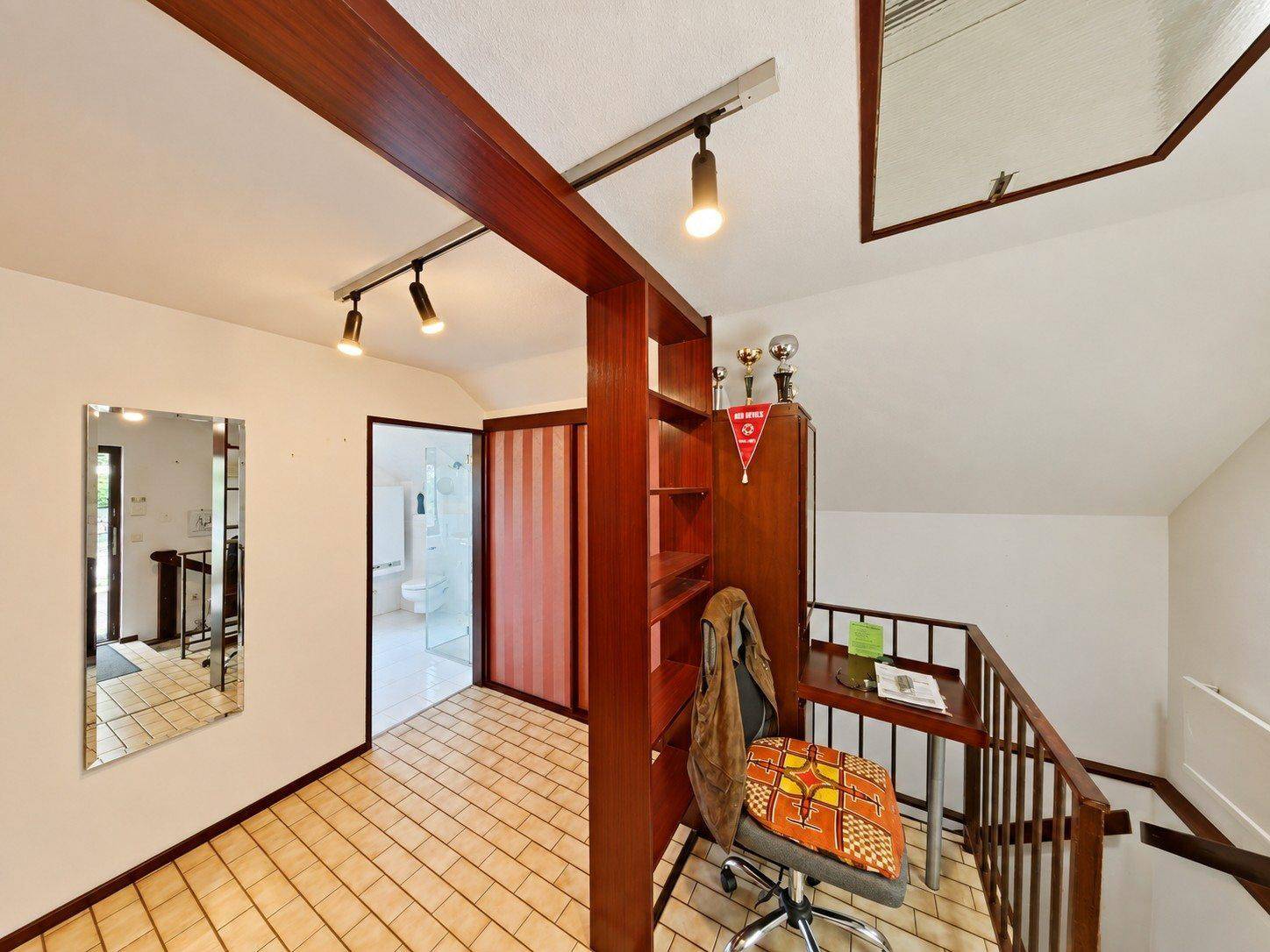 Heller Flur im Obergeschoss mit Holzdetails, Fliesenboden und kleinem Arbeitsbereich.
