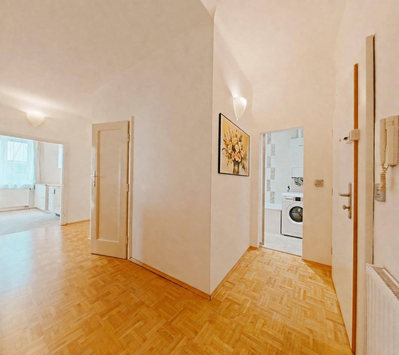 Heller Flur mit Parkettboden, mehreren Türen und Blick in ein Badezimmer.