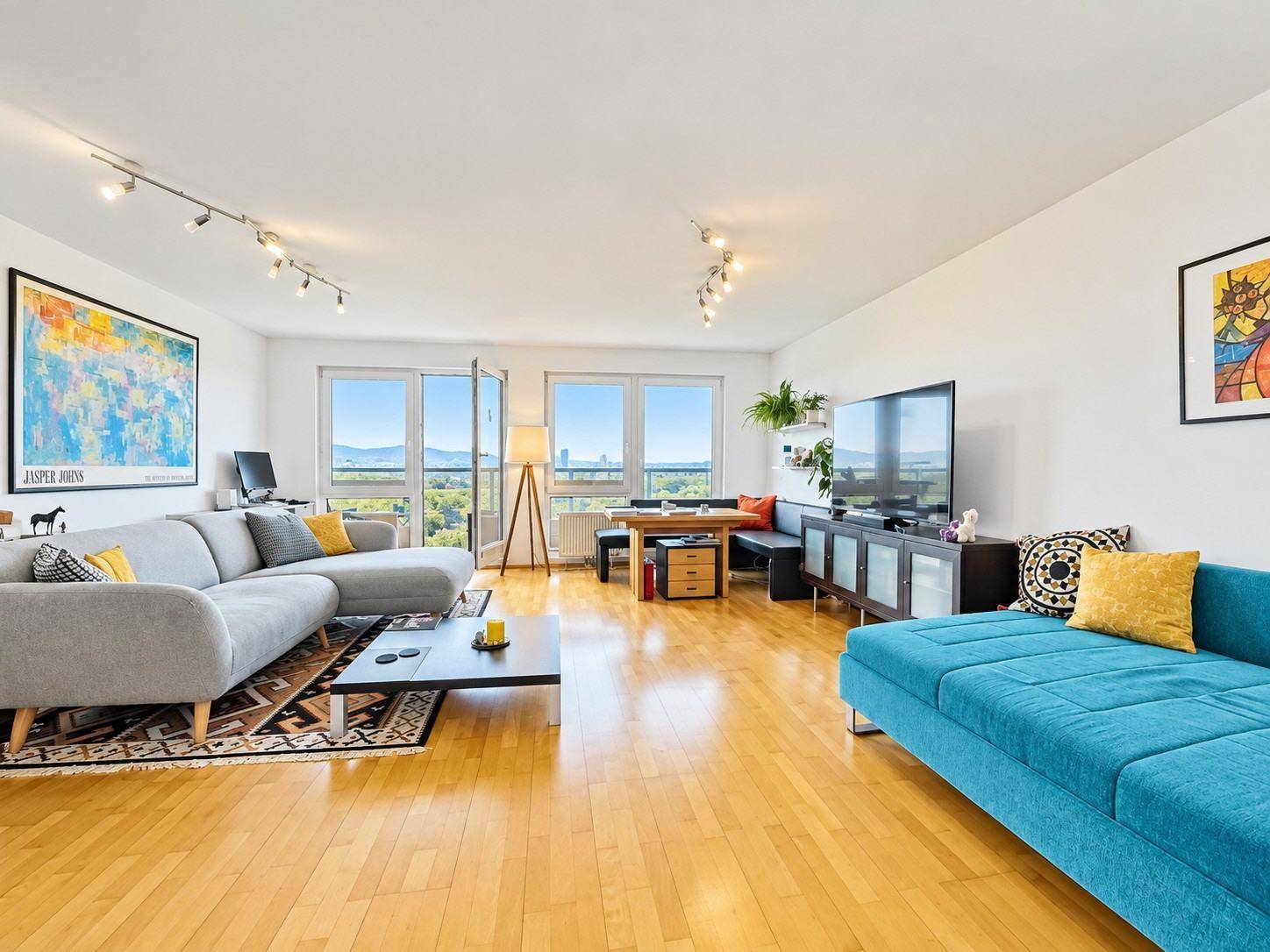 Heller, offener Wohn- und Essbereich mit Holzboden, modernen Sofas und weitem Ausblick.