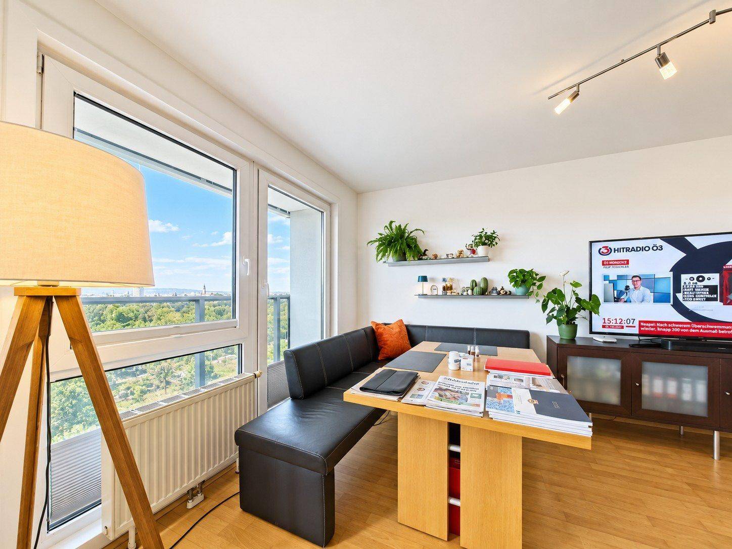 Gemütlicher Essbereich mit Sitzbank, Holzboden und großen Fenstern mit Blick ins Grüne.