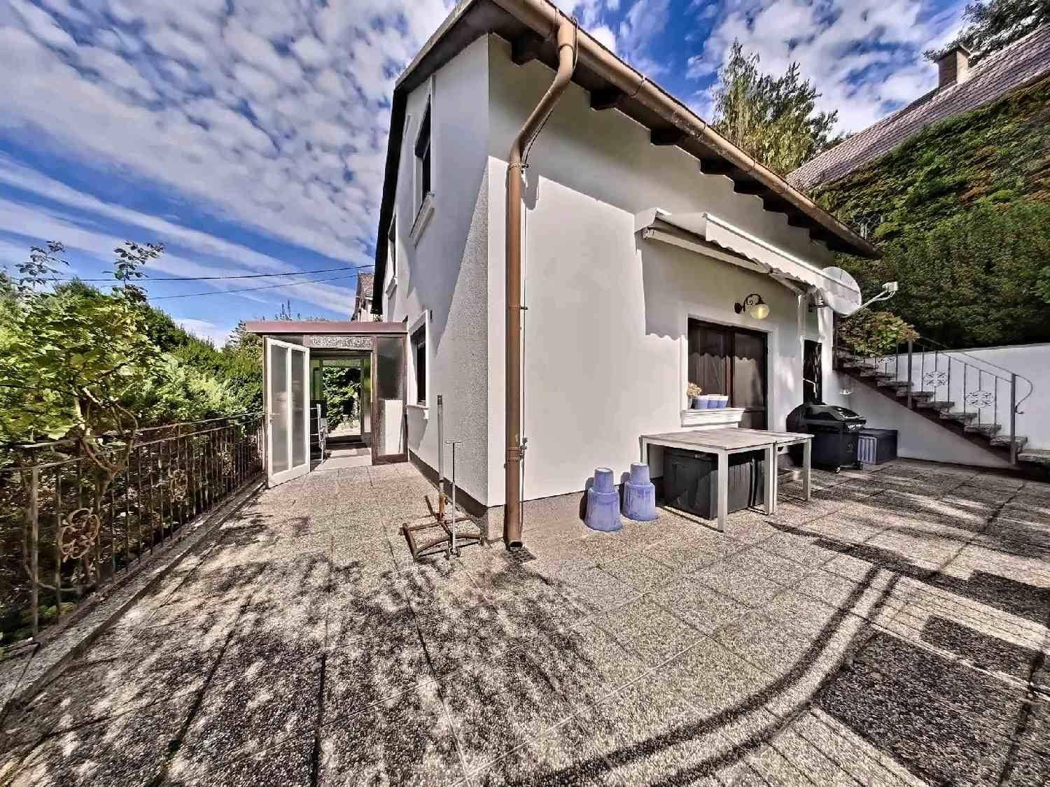 Seitenansicht des Hauses mit gepflastertem Außenbereich und Zugang zum Wintergarten.