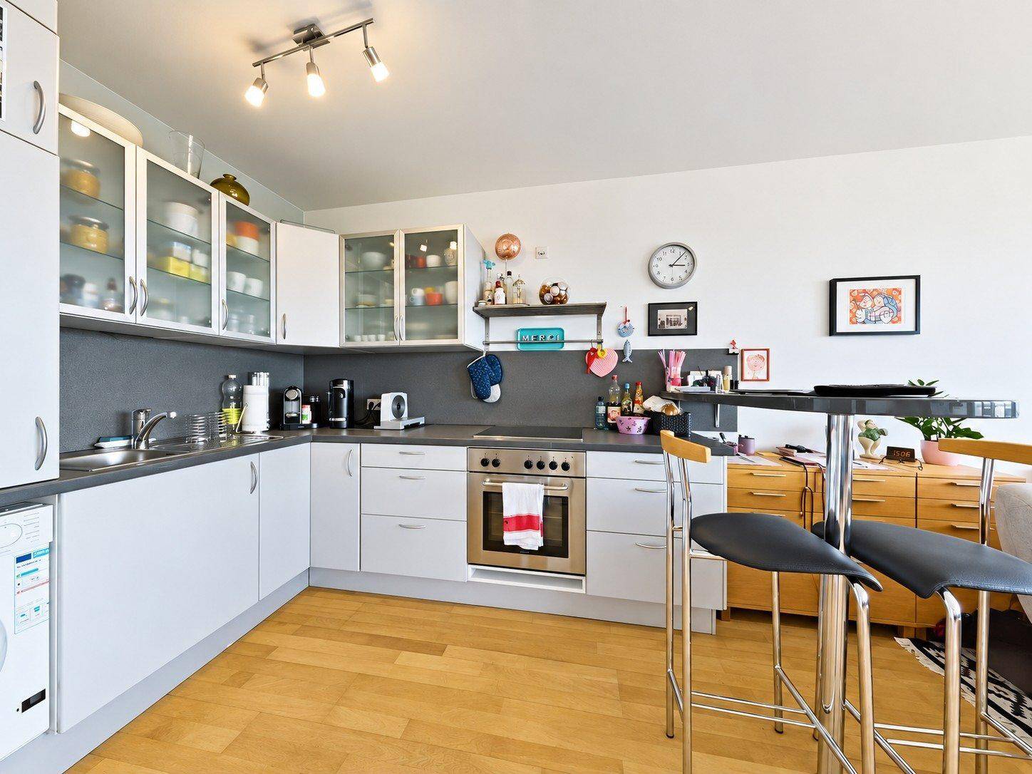 Moderne Küche mit weißen Schränken, integriertem Backofen und praktischer Frühstücksbar.