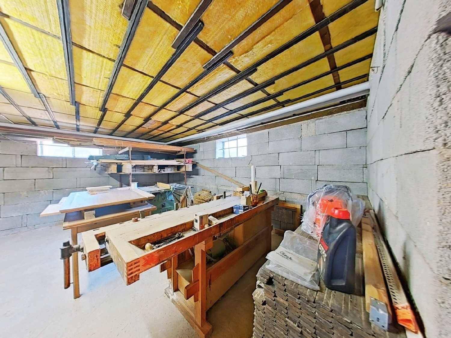 Großer Kellerraum, eingerichtet als Werkstatt mit Werkbänken und Baumaterialien.