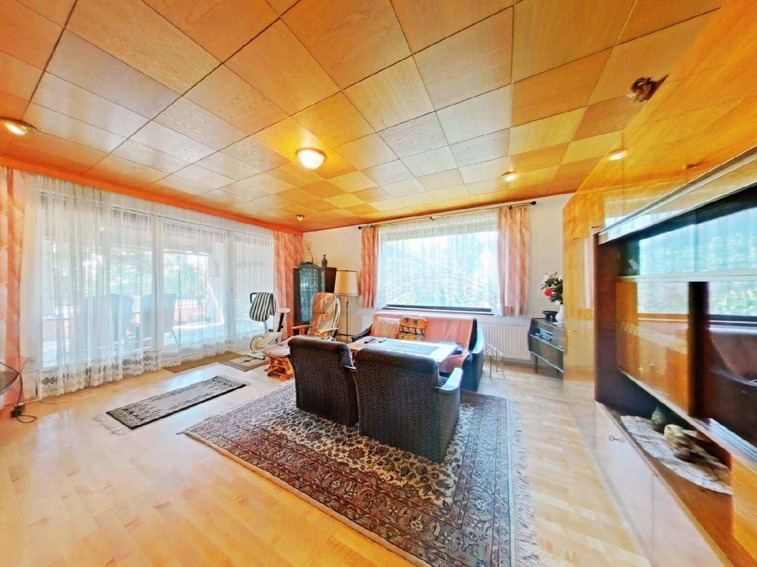 Geräumiges Wohnzimmer mit Holzdecke, Parkettboden und Zugang zu einer Terrasse.